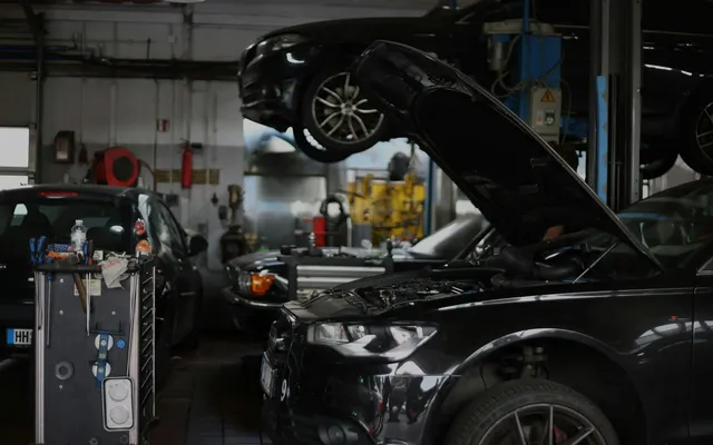 Czarne Audi z otwartą maską w europejskim warsztacie